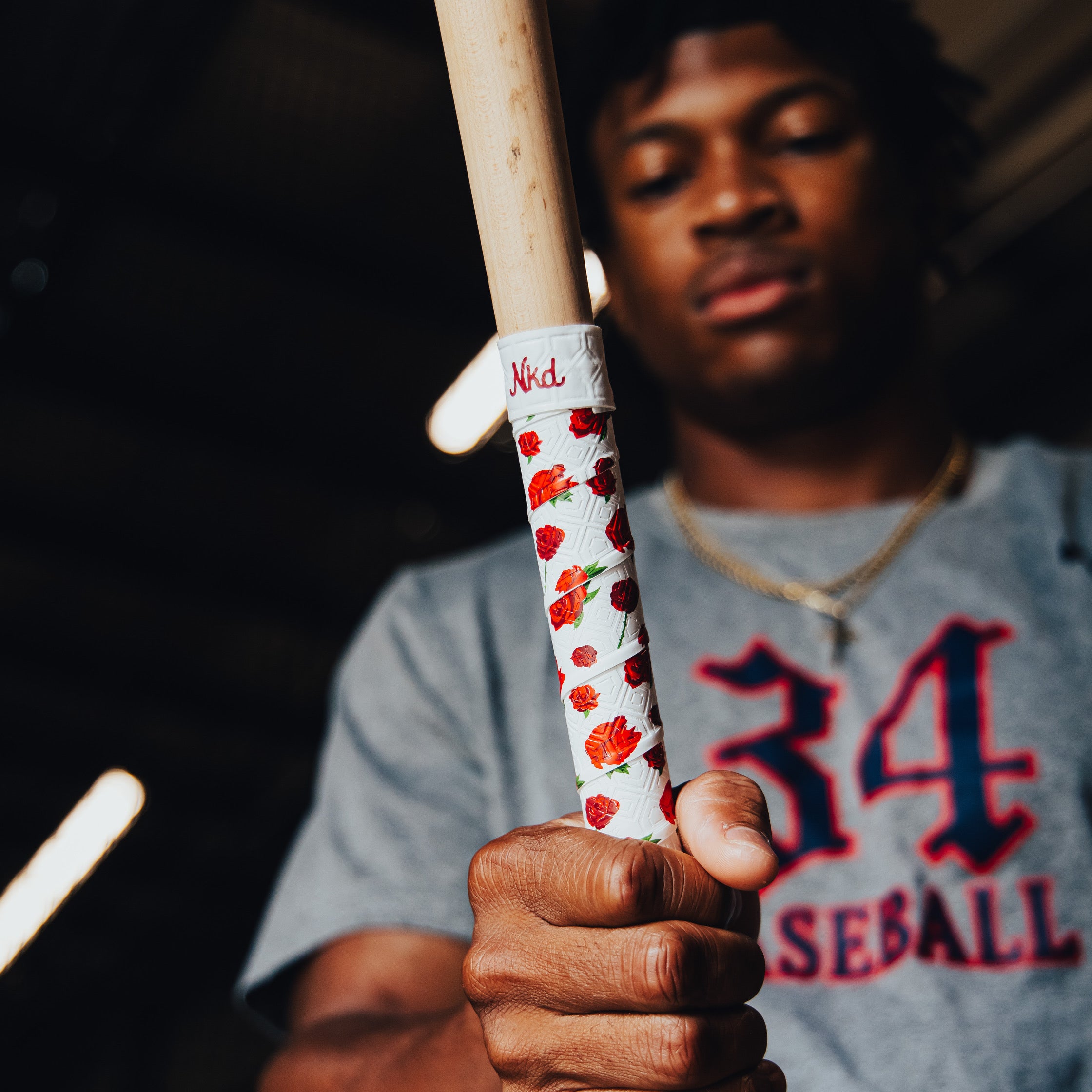 Photo of a wooden bat wrapped in the roses bat grip being help be a baseball player.