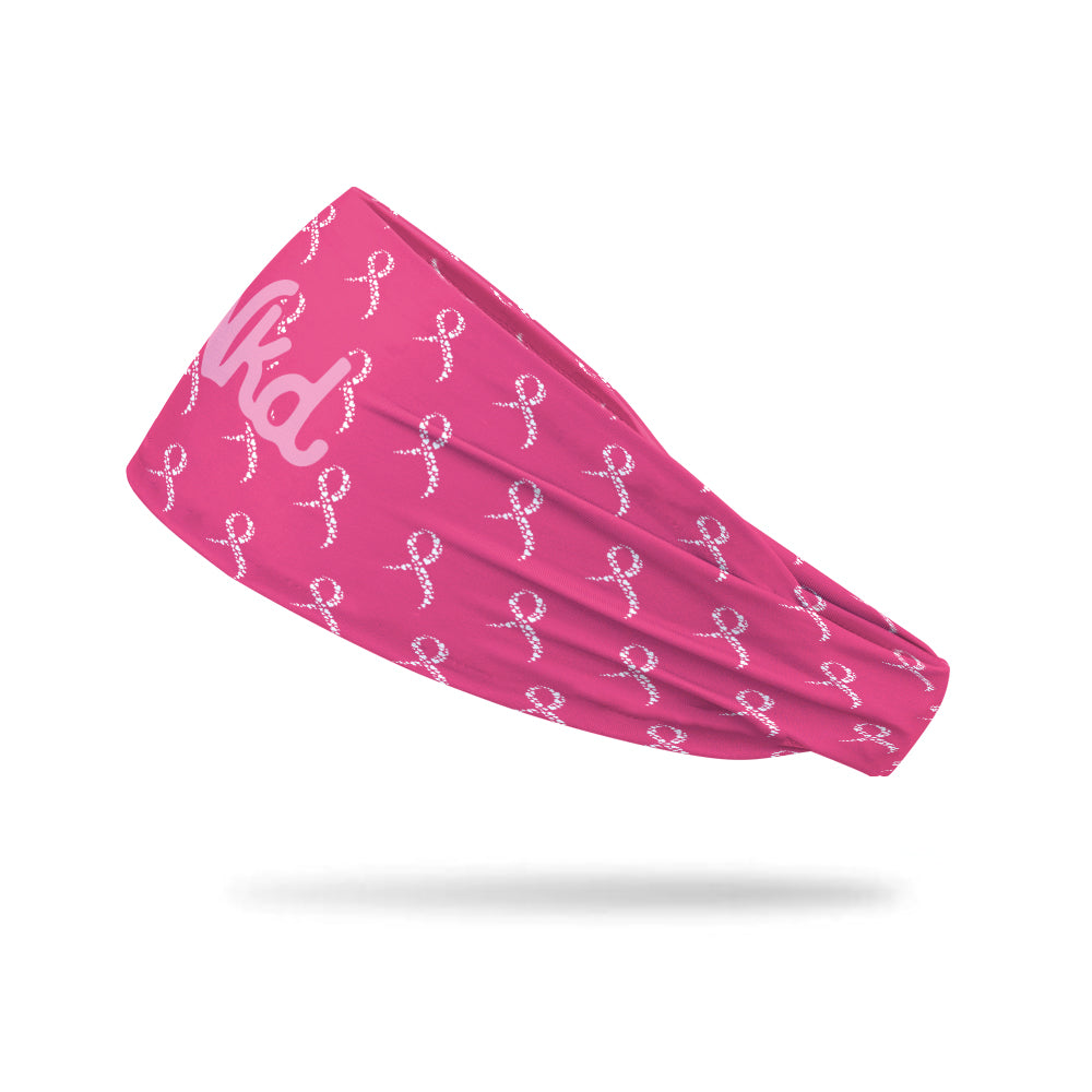 Photo of a pink headband decorated with white hearts in the shape of ribbons on a white background.