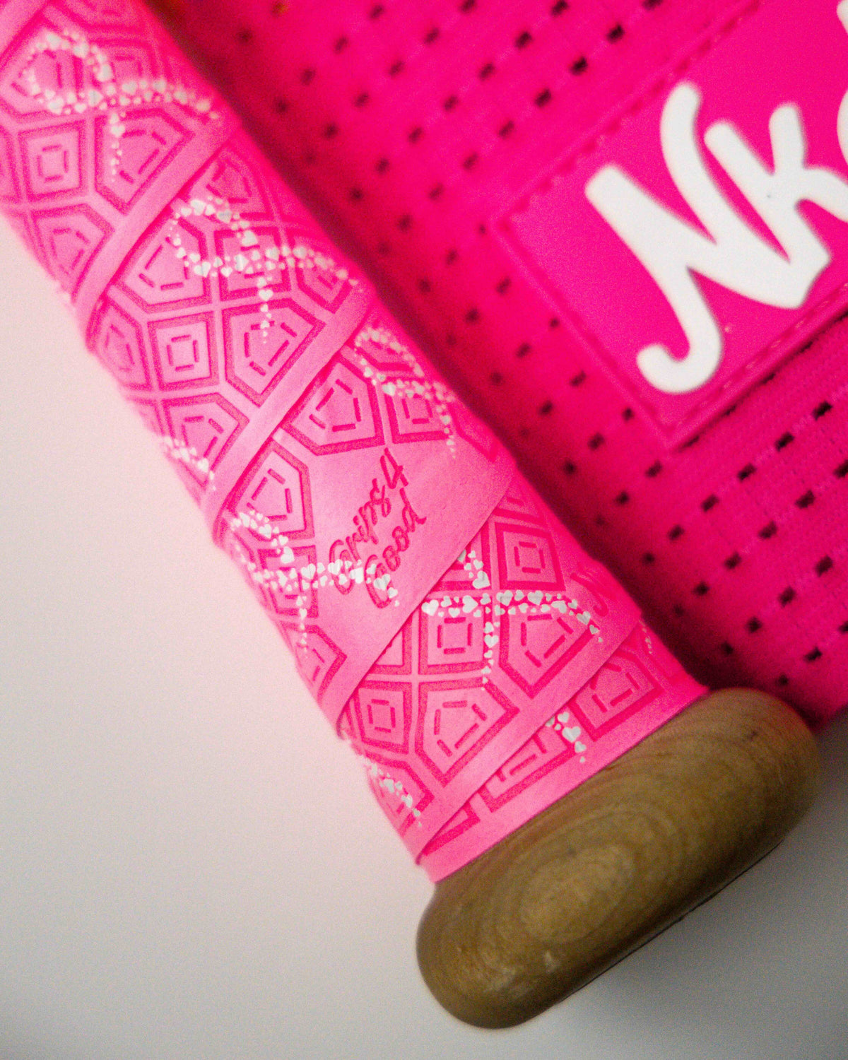 Photo of bright pink "Ribbons of Strength" bat grip on a bat handle. Grip is bright pink with white hearts on it that make the shape of a ribbon in honor of breast cancer survivors and those still fighting the disease.