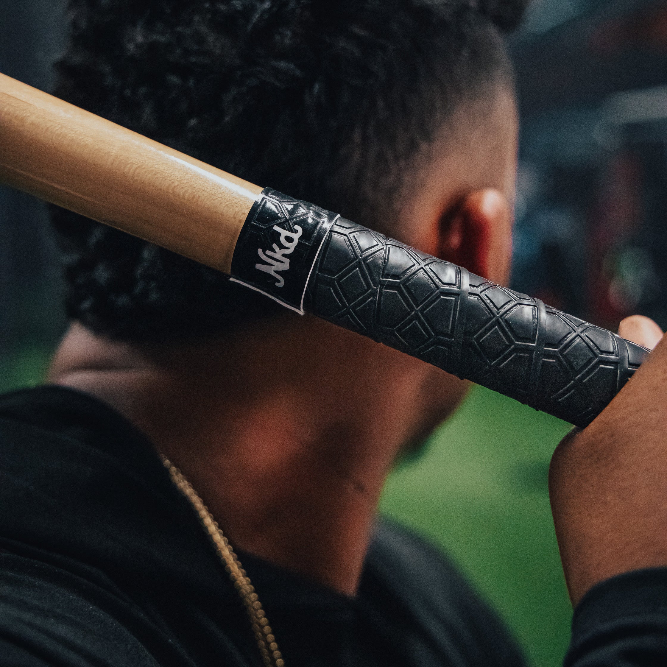 Photo of a man holding a bat behind his head that is wrapped in the jet black naked bat grip.
