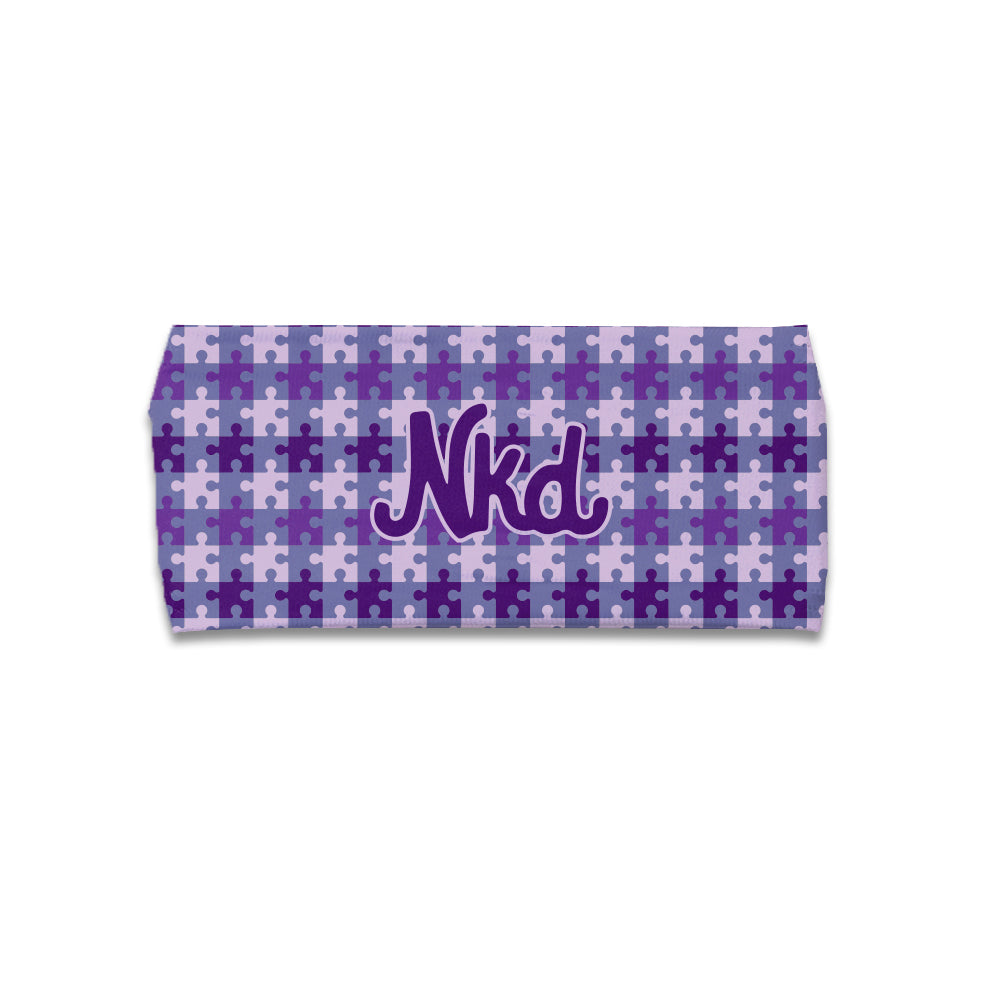 Photo of a headband decorated with various purple puzzle pieces and the NKD logo in the middle on a white background. 