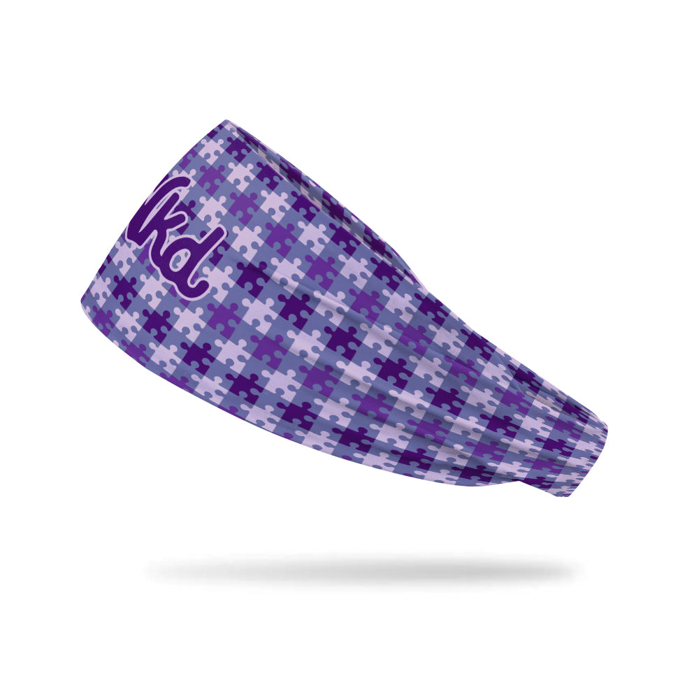 Photo of a headband from the side decorated with various purple puzzle pieces on a white background.