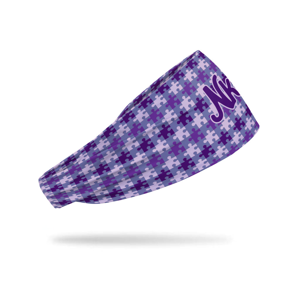Photo of a headband from the side decorated with various purple puzzle pieces on a white background. 