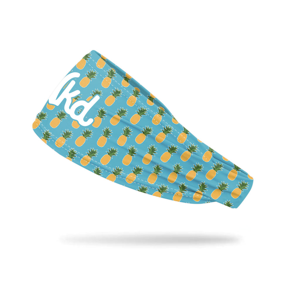 Photo of a blue headband with a pineapple pattern printed on all over while floating on a white background.