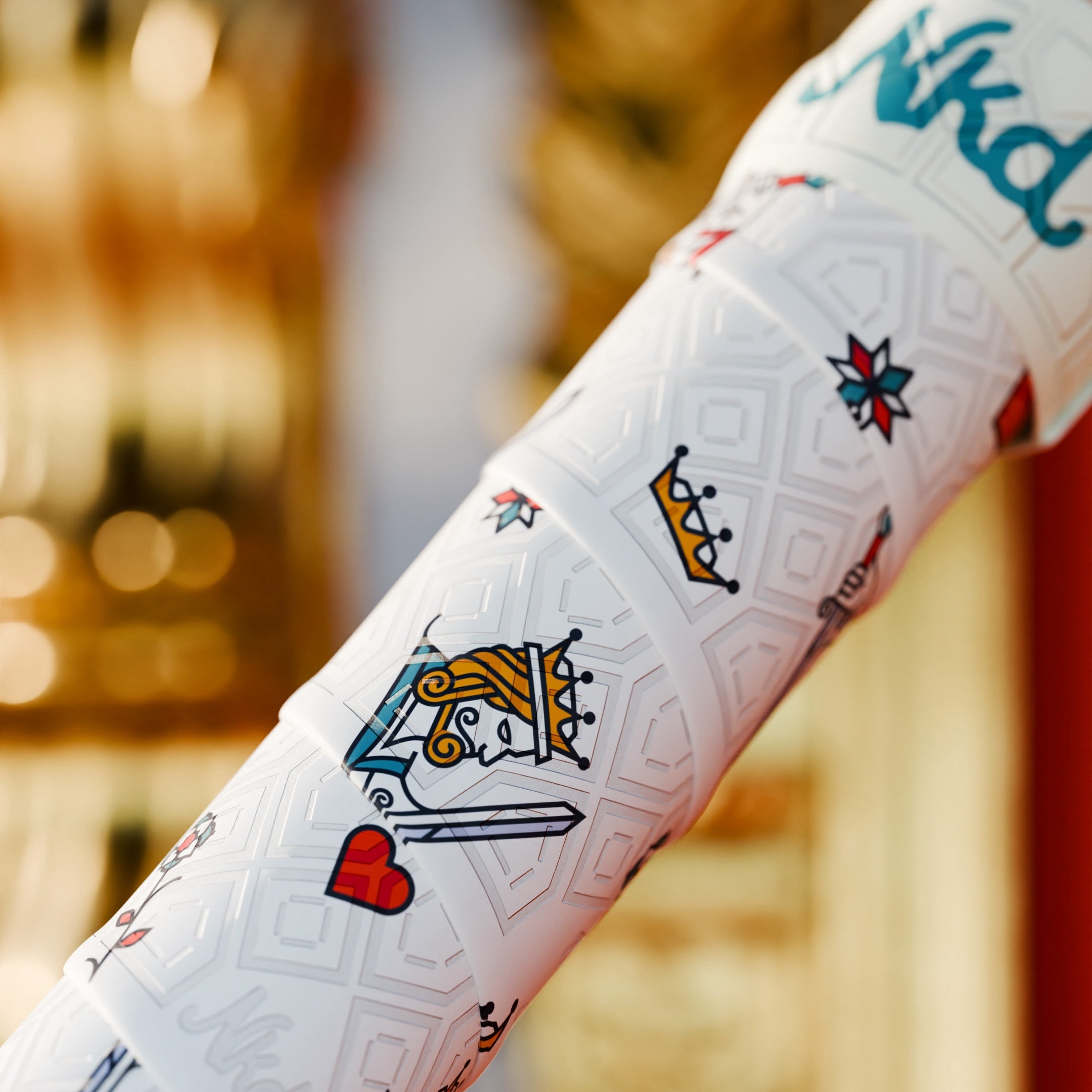 Photo of the King of hearts bat grip on a bat with a colorful out of focus background. 