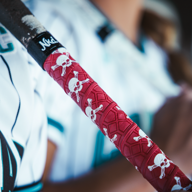 Photo of the a bat wrapped in the skull bat grip leaning against sports jerseys.