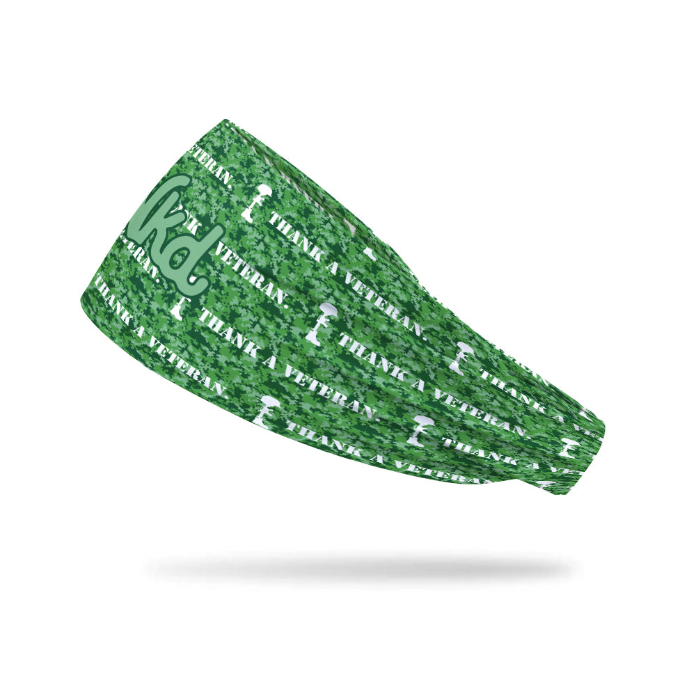 Photo of a headband decorated with digital camouflage in various shades of green with the words Thank a veteran written on it.